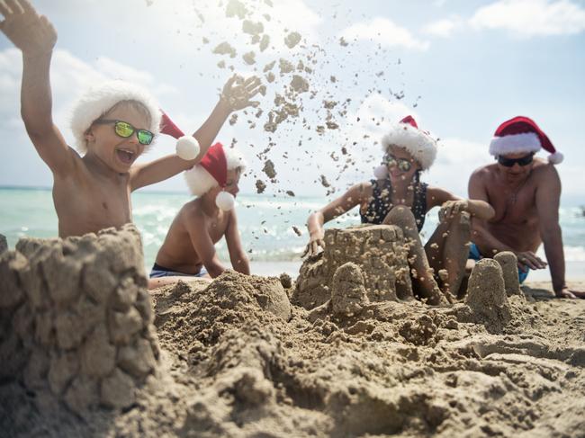 SHFG summer. It's summer Christmas on the beach. Kids and grandfather wearing Santa hats are building sandcastles on the beach. Picture: iStock