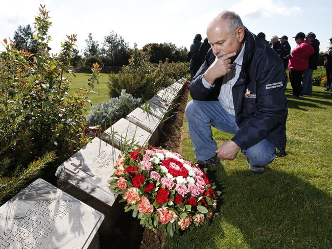 Family ties ... Joe Drobinski, descendant of Private Reginald Healy 1st Battalion Australian Infantry, lays a wreath at his relative's head stone at Baby 700 Cemetery. Picture: David Caird