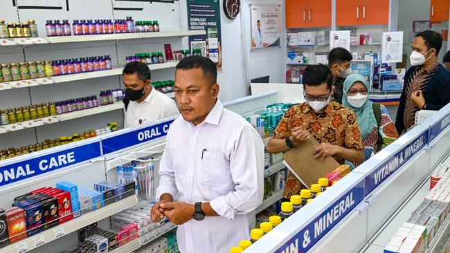 Police officers visit a pharmacy in the Indonesian city of Banda Aceh to inspect syrup formulas for children, following numerous child deaths from kidney injuries. Picture: AFP