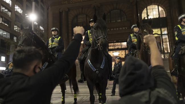 Protestors in Sydney raise their fists as they stand before mounted police during a Black Lives Matter rally in solidarity with US demonstators over the death of George Floyd.