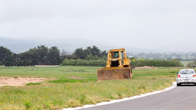 A dozer sits in a housing estate with the farm in the background. Picture: Mark Stewart