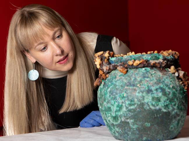 Curator Lily Withycombe examining pot, within the Pompeii exhibition.