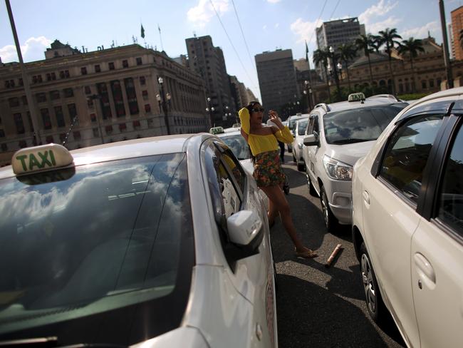 A woman walks between taxis blocking Cha viaduct to protest against online car-sharing service Uber, in front of the city hall of Sao Paulo, Brazil, October 8, 2015. Sao Paulo will introduce new regulations to govern ride-sharing services such as Uber instead of backing an outright ban proposed by local Brazilian lawmakers, the mayor of South America's biggest city said on Thursday. REUTERS/Nacho Doce