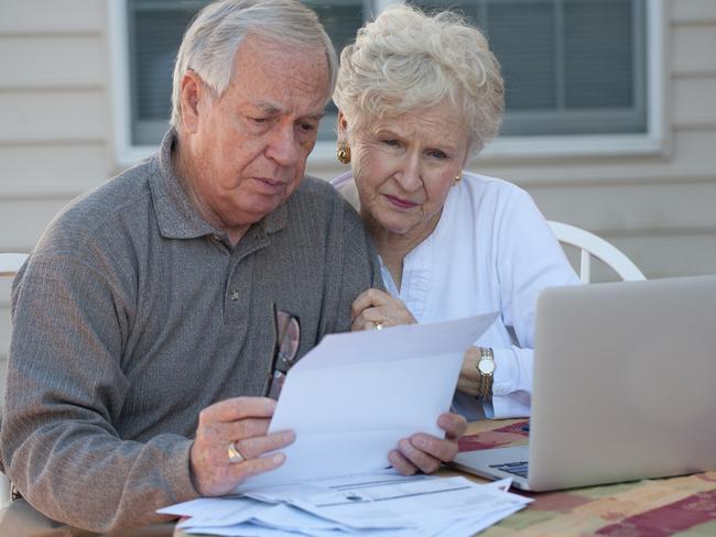 Senior couple working on home / personal finance using laptop with concerned expression; retirement money generic