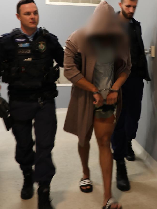 A hooded Atteya is walked into Liverpool Police Station on Wednesday morning. Picture: NSW Police