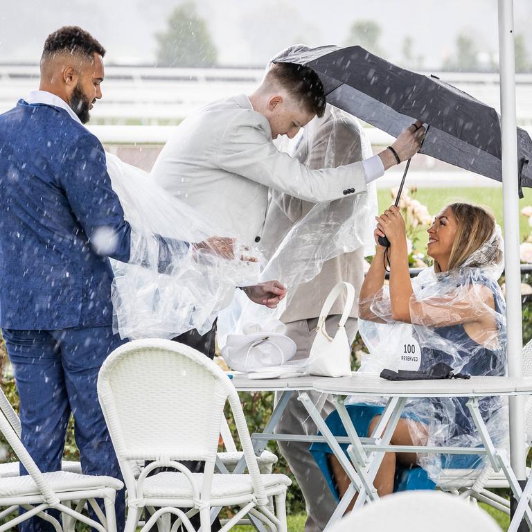 Punters shelter from the rain. Picture: Jake Nowakowski