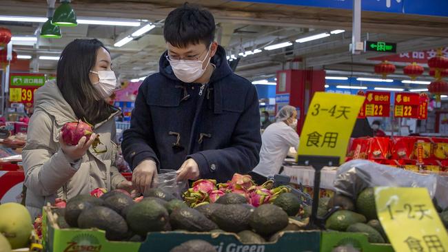 People wear face masks as they shop at a grocery store in Beijing on Saturday. Picture: AP