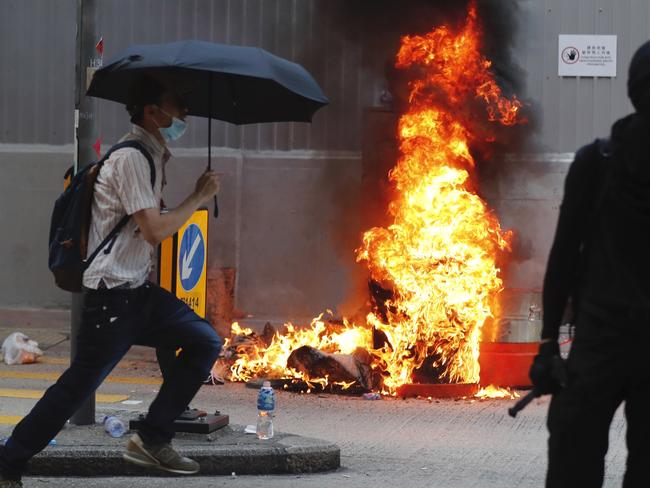 A black-clad protester stands by flames rising from a fire in Hong Kong. Picture: AP