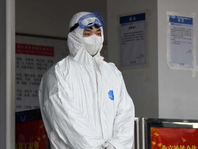 A security personnel wearing protective clothing to help stop the spread of a deadly SARS-like virus which originated in the central city of Wuhan is seenseen at the entrance of subway station in Beijing on January 28, 2020. - The deadly new coronavirus that has broken out in China, 2019-nCoV, will afflict a minimum of tens of thousands of people and will last at least several months, researchers estimate based on the first available data. (Photo by NOEL CELIS / AFP)