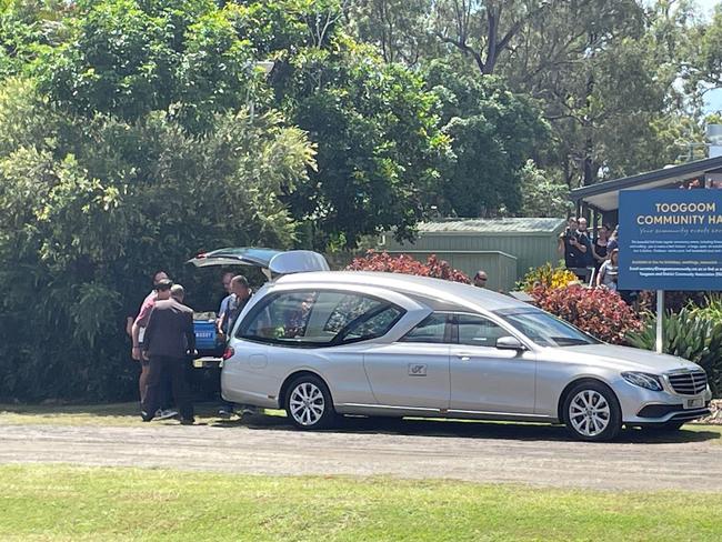 The casket getting loaded into back of the hearse after a funeral.