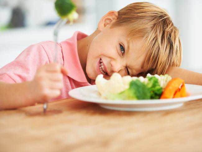 Portrait of a cute young boy looking naughty while holding a piece of broccoli on his fork