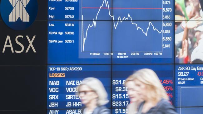 People walking past the display board of the Sydney Exchange Square.