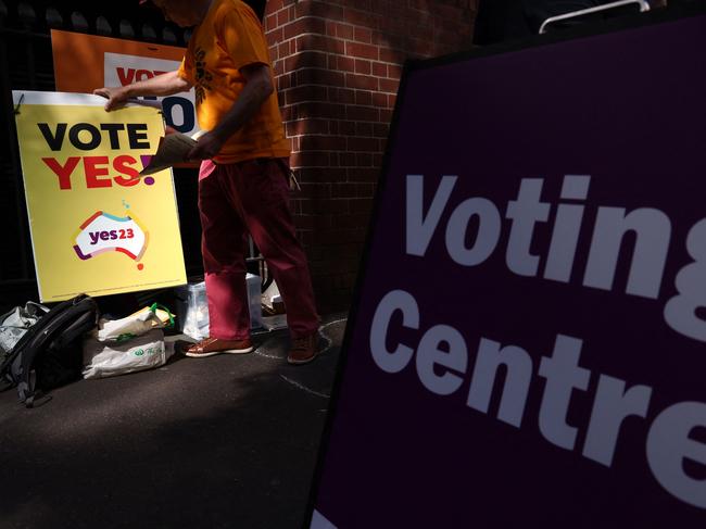 A volunteer moves a poster as he hands out voting brochures outside a voting centre in central Sydney on October 3, 2023. Early voting opened on October 3 across a swathe of Australia on a reform that would recognise Indigenous people in the 1901 constitution for the first time. (Photo by DAVID GRAY / AFP)