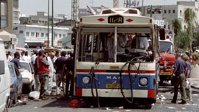 Israeli police officers and rescuers gathered around the wreck of a bus following a bomb attack in July 1995. Picture:AFP/Getty Images