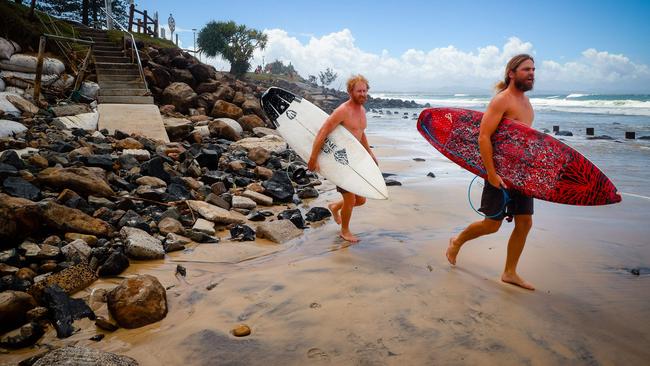 Two surfers negotiate massive beach erosion in the wake of cyclonic conditions at Byron Bay Main Beach on December 15, 2020, after wild weather lashed Australia's Northern New South Wales and South East Queensland with heavy rain, strong winds and king tides. (Photo by Patrick HAMILTON / AFP)