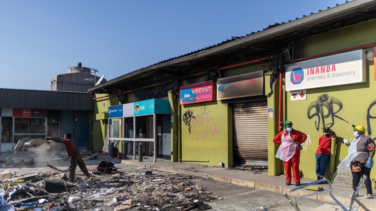 Inanda community members use light torches to clean up from debris the interior of the looted Dube Village Mall in Durban on July 17, 2021. Picture: Guillem Sartorio, AFP.