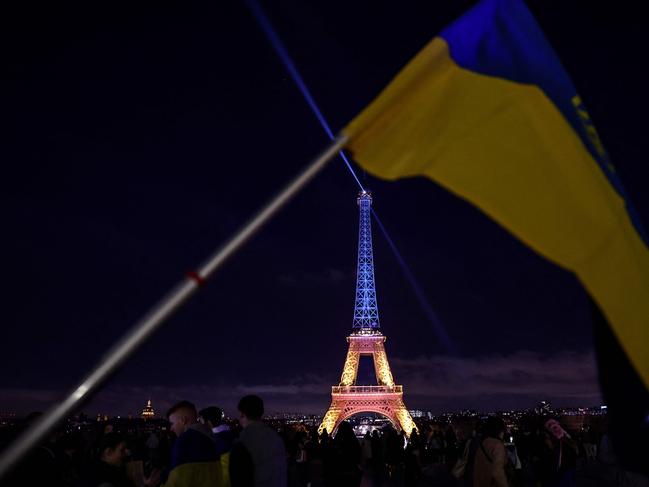 The Eiffel Tower lit in the colours of the Ukrainian flag, seen from behind a Ukrainian flag, to mark the third anniversary of the invasion by Russia of Ukraine. Picture: AFP