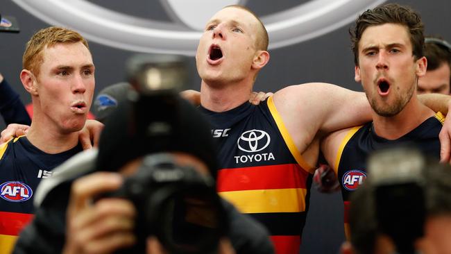 Sam Jacobs of the Crows sings the team song with Tom Lynch and Kyle Hartigan.