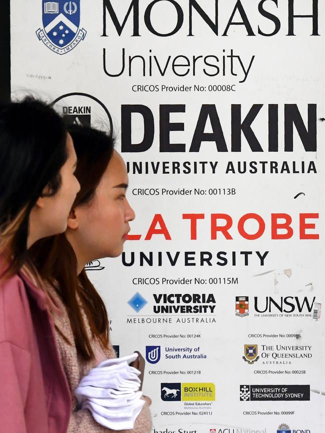 People walk past signage for Australian universities in Melbourne’s CBD. Picture: AFP