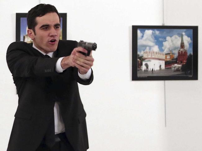 An unnamed gunman points his gun, after shooting the Russian Ambassador to Turkey, Andrei Karlov, at a photo gallery in Ankara, Turkey, Monday, Dec. 19, 2016. A gunman in a suit and tie shouted slogans about Syria's civil war after he killed Russia's ambassador to Turkey in front of stunned onlookers at a photo exhibition in the Turkish capital on Monday, according to an Associated Press photographer who witnessed the shooting. Police later killed the assailant, Turkish station NTV reported. (AP Photo/Burhan Ozbilici)