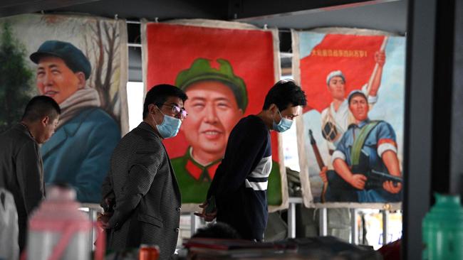 People walk past pictures depicting the late Chinese Communist leader Mao Zedong at a stall in the Panjiayuan antique market in Beijing. Picture: AFP