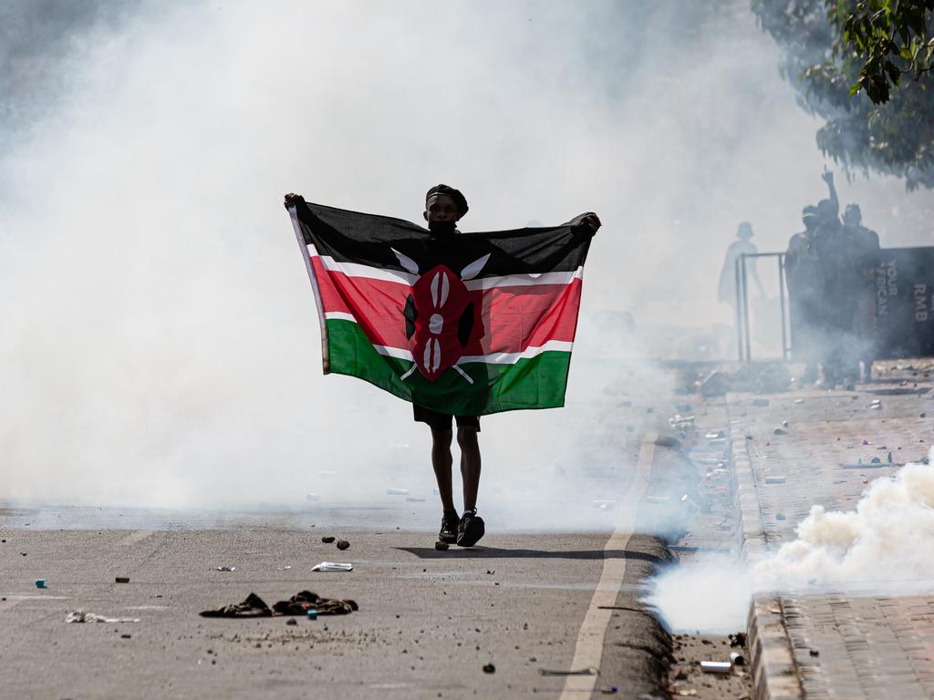 A protester carries a Kenyan flag walks through the madness.
