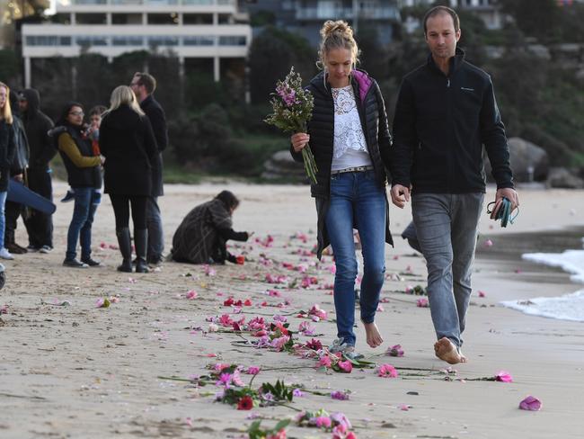 Family and friends gather on Freshwater Beach following a candlelight vigil, where they threw hundreds of pink flowers into the ocean for Justine Damond in Sydney.  Picture:  AAP