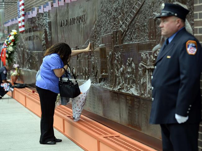 A woman lays flowers at the Fire Department of New York (FDNY) Memorial Wall on the 13th anniversary of the September 11, 2001 attacks. Picture: Timothy A. Clary