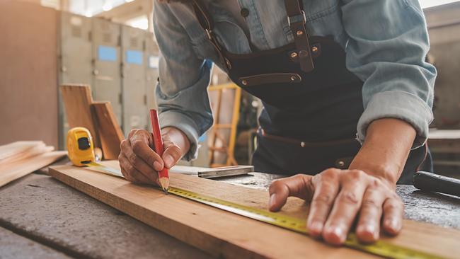 TRADESMAN/ TRADIE/BUILDING INDUSTRY: Carpenter working with equipment on wooden table in carpentry shop. woman works in a carpentry shop.