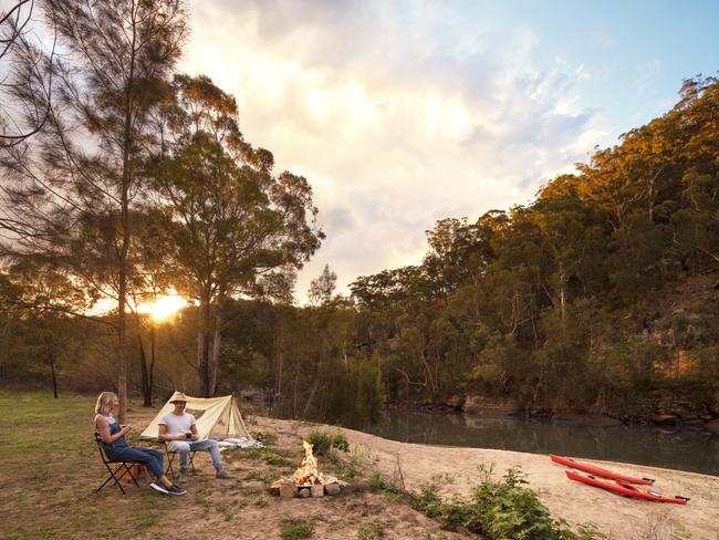 ESCAPE:  Couple enjoying a campfire by their text on the Hawkesbury River in Lower MacDonald. Picture:  Destination NSW