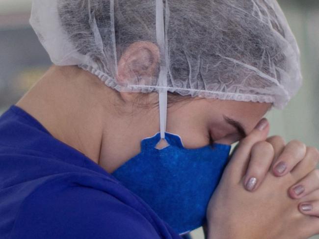 A hospital worker prays as health workers from the Portuguese charity hospital in Belem, Para State, Brazil, sing and pray for colleagues and COVID-19 patients inside the hospital wards and ICU areas as part of Easter celebrations, on April 4, 2021. (Photo by Tarso SARRAF / AFP)