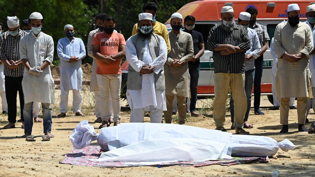 Relatives and friends pray during funeral of coronavirus victim at a graveyard in New Delhi. Picture: AFP