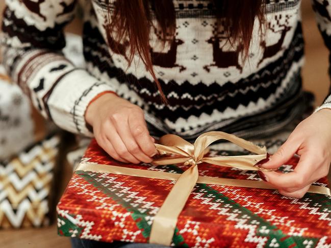 woman in sweaters with deers openning christmas presents under tree closeup. stylish gift ideas. seasonal greetings concept. joyful moment. space for text Picture: IStock