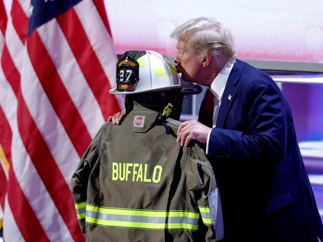 Former US President and 2024 Republican presidential candidate Donald Trump kisses a helmet and firefighter's jacket that belonged to Corey Comperatore, who was fatally shot at a rally where Trump survived an assassination attempt, as he accepts his party's nomination on the last day of the 2024 Republican National Convention at the Fiserv Forum in Milwaukee, Wisconsin, on July 18, 2024. Comperatore, a 50-year-old firefighter and father of two, died shielding his family from the gunshots. Days after he survived an assassination attempt Trump won formal nomination as the Republican presidential candidate and picked Ohio US Senator J.D. Vance for running mate. (Photo by Kamil Krzaczynski / AFP)