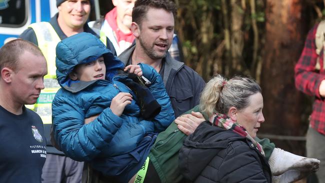 A shoeless William is carried to safety by his mother Penny Callaghan and her partner, Nathan Ezard. Picture: David Crosling