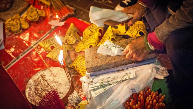 A paper effigy being whacked with a slipper during a villain hitting ceremony in Hong Kong. Picture: Alamy