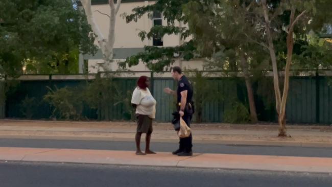 Constable Bradley Lynch speaks to a woman after confiscating the group’s alcohol.