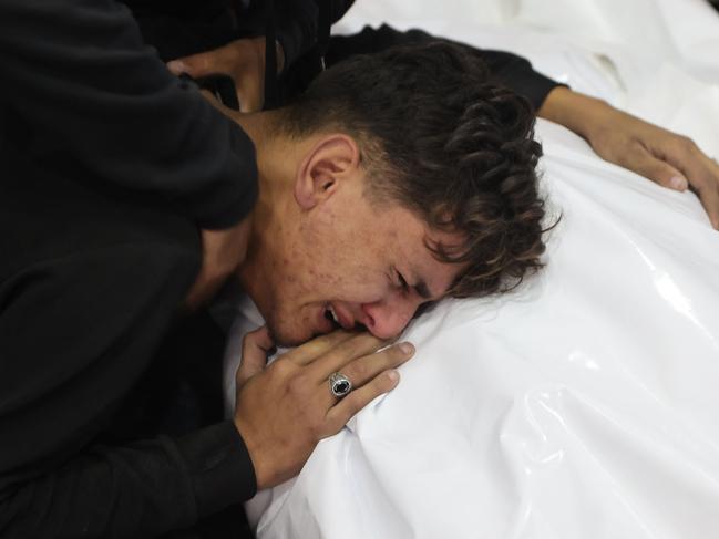 A youth mourns by the covered body of a relative killed in an Israeli strike that destroyed a house on al-Jalaa street in central Gaza City. Picture: AFP