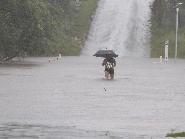 Heavy rain has moved into the South East thanks to TC Alfred bringing flooding. A man walks out of a flooded Schmidt road at Logan Reserve. Pics Adam Head