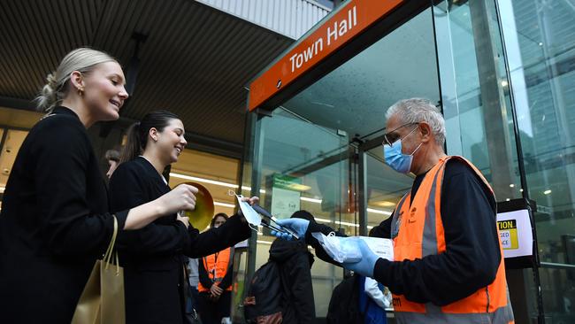 A NSW Transport worker hands out face masks to commuters at Town Hall station in Sydney on Thursday as restrictions were reintroduced. Picture: AAP