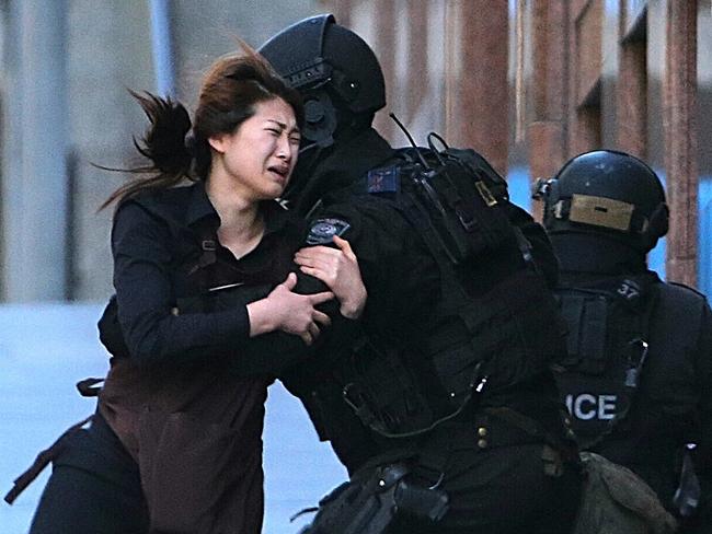 A hostage runs to armed tactical response police officers for safety after she escaped from a cafe under siege. Picture: Rob Griffith