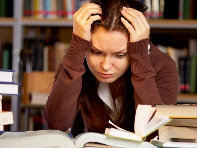 Portrait of troubled girl touching head while preparing for seminar in college library stressed high school kids . Picture: istock