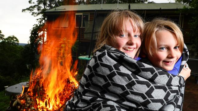 Siblings Jude and Ayla Barry rug up by the fire at Ninderry as the mercury plummets across southeast Queensland. Picture: Lachie Millard