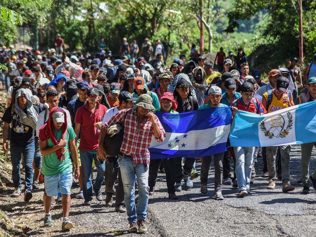 TOPSHOT - Honduran migrants take part in a new caravan heading to the US with Honduran and Guatemalan national flags in Quezaltepeque, Chiquimula, Guatemala on October 22, 2018. - US President Donald Trump on Monday called the migrant caravan heading toward the US-Mexico border a national emergency, saying he has alerted the US border patrol and military. (Photo by ORLANDO ESTRADA / AFP)