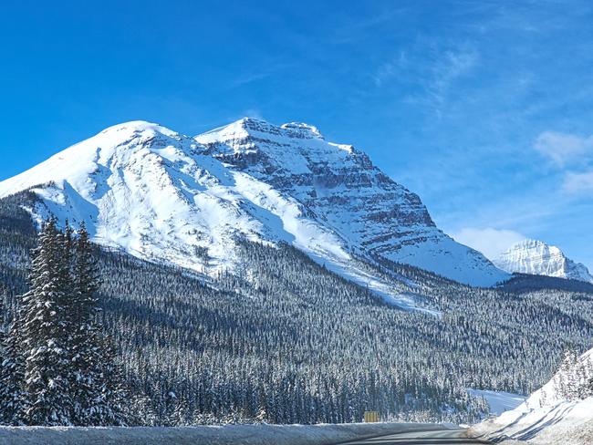 ESCAPE: Canada's Winter Wonderland, Kristie Kellahan - empty road, with snowy mountains and trees at Banff Canada  Picture: Istock