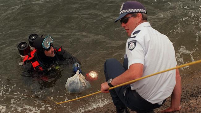 Police divers retrieve a plastic bag containing clothing out of Blue Rock Lake at Moe.