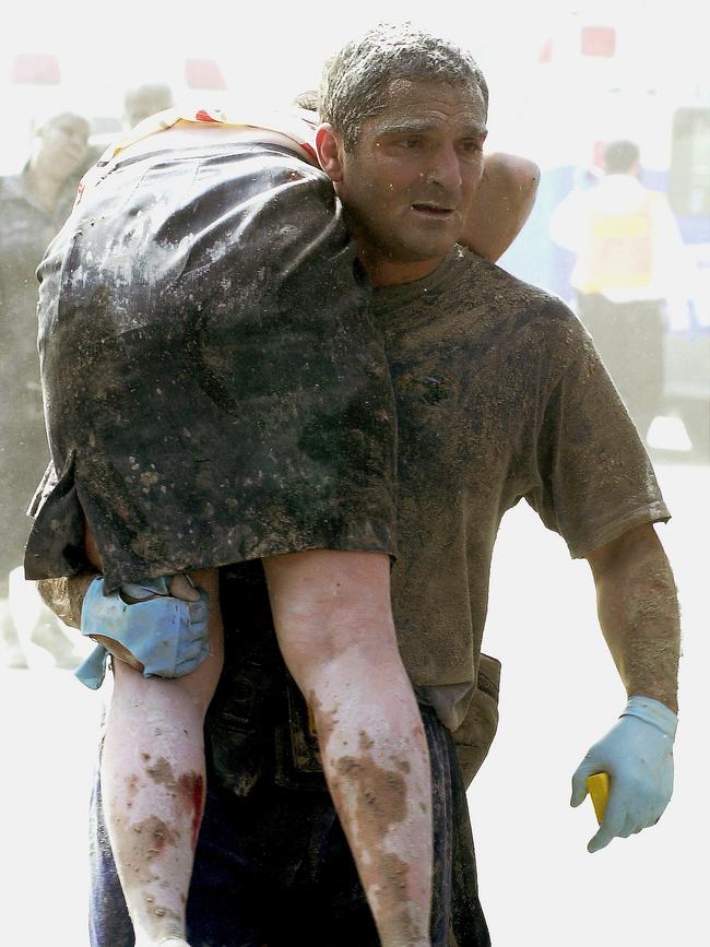 Secret Service agent Thomas Armas carries an injured woman to ambulance after Tower One of the World Trade Center collapsed.