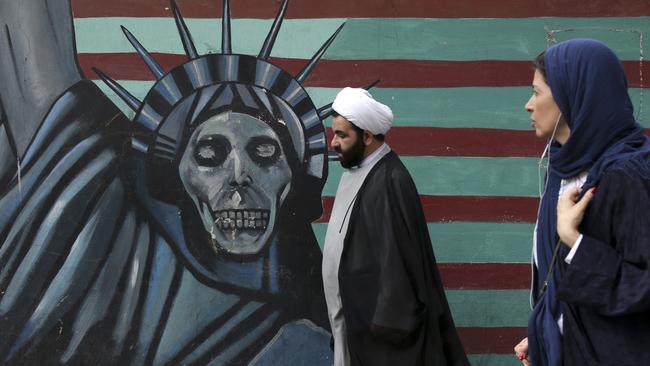 A cleric and a woman walk past an anti-U.S. mural painted on the wall of the former U.S. Embassy in Tehran, Iran, Tuesday, May. 8, 2018. President Donald Trump prepared to tell the world Tuesday whether he plans to follow through on his campaign threat to pull out of the landmark nuclear accord with Iran, as European allies braced for the potential fallout after a last-ditch persuasion effort. (AP Photo/Vahid Salemi)