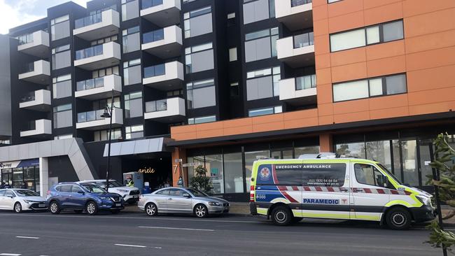 An ambulance has arrived at the Ariele apartment complex in Maribyrnong. Paramedics wearing hazmat suits are preparing to enter the building where four residents have tested positive.