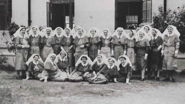 Wartime nurses pose outside hospital.